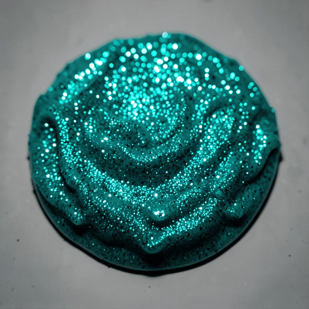 Sparkly glitter slime in a child's hands, bright pink and purple tones, playful and creative mood